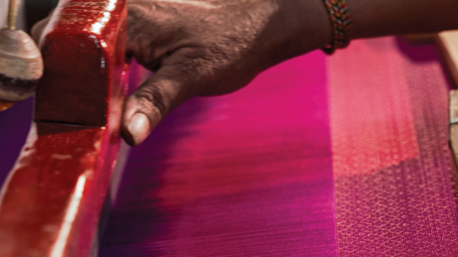 A close up of hands weaving silk threads