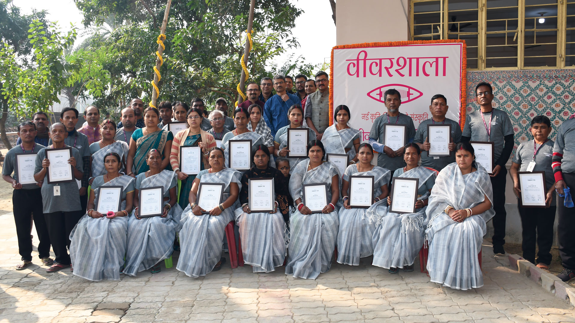 A group of weavers in front of a weavershala building