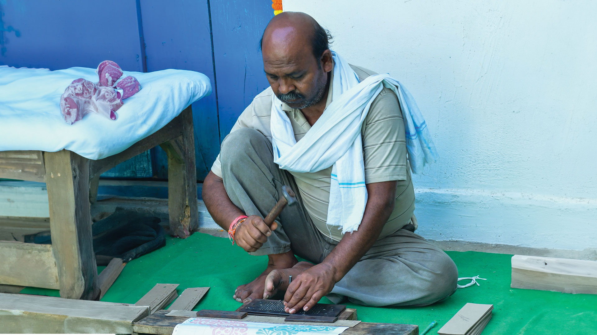 A cratsman punching out a design on a cardboard stencil