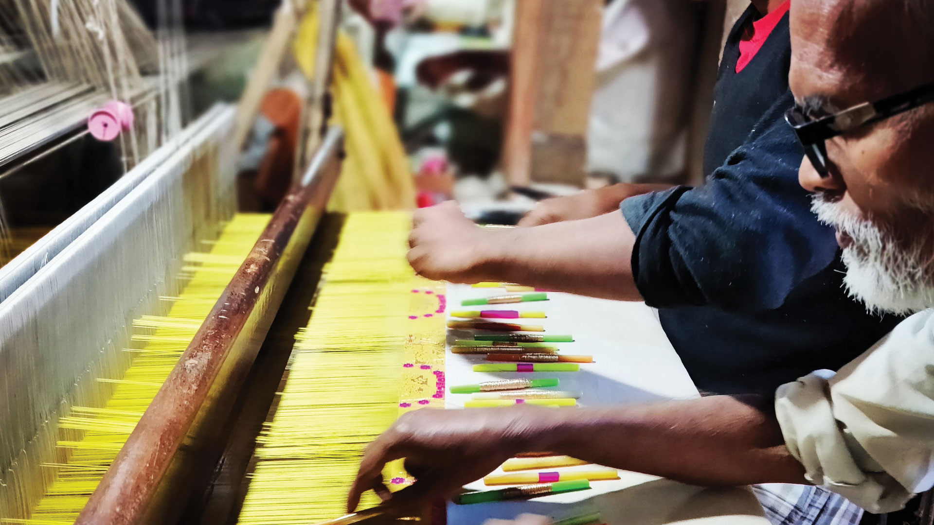 Craftsmen adding gold threads to a cotton saree